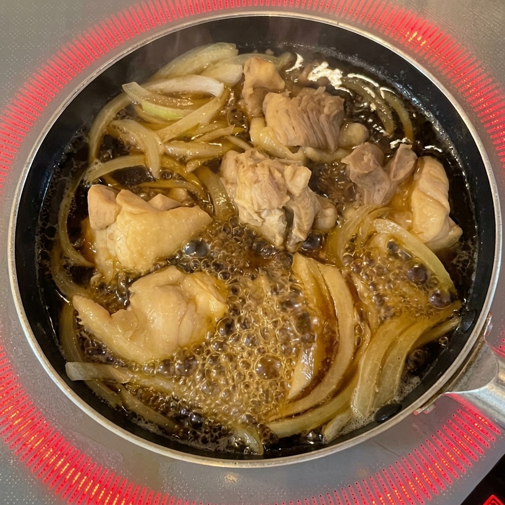 Verquirltes Ei wird in kreisenden Bewegungen aus einer Schale über Hähnchen und Zwiebeln in der Pfanne gegossen.