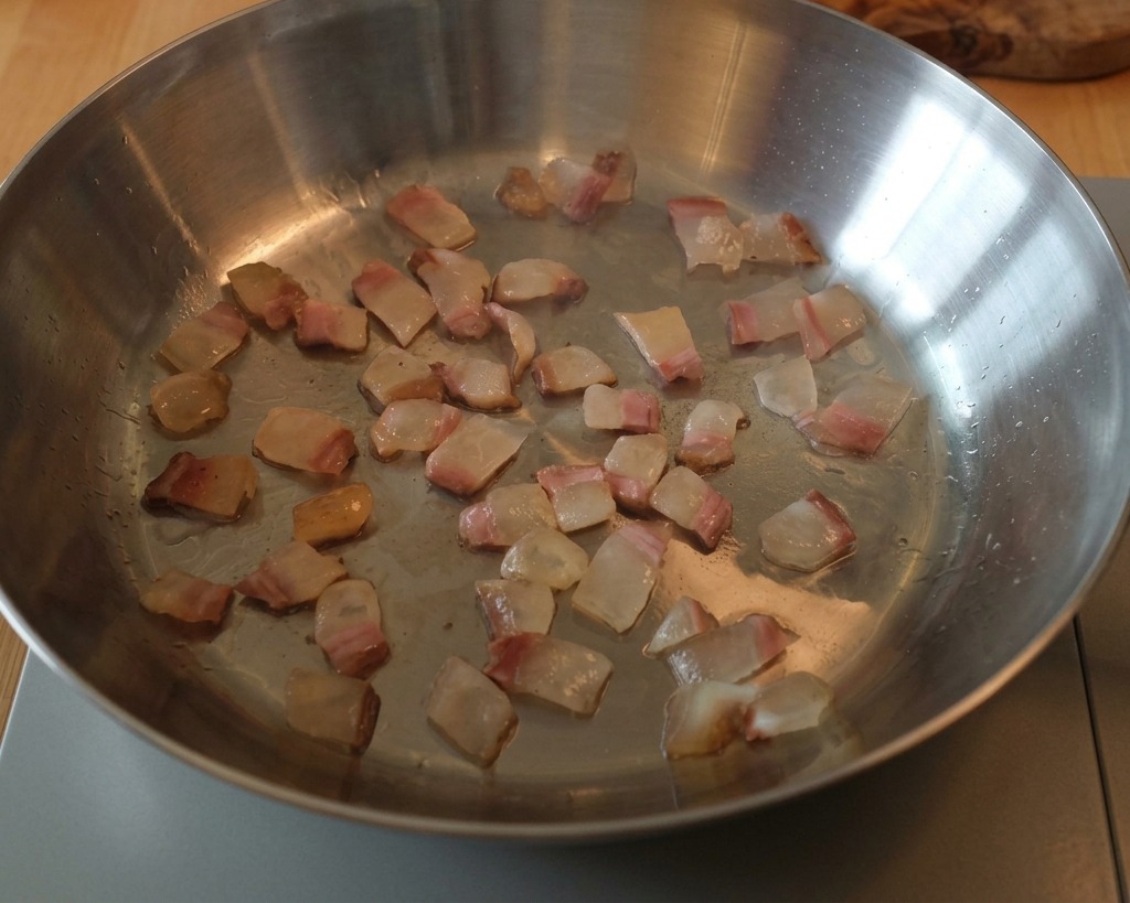 Guanciale-Würfel in einer Pfanne, während das Fett flüssig wird.