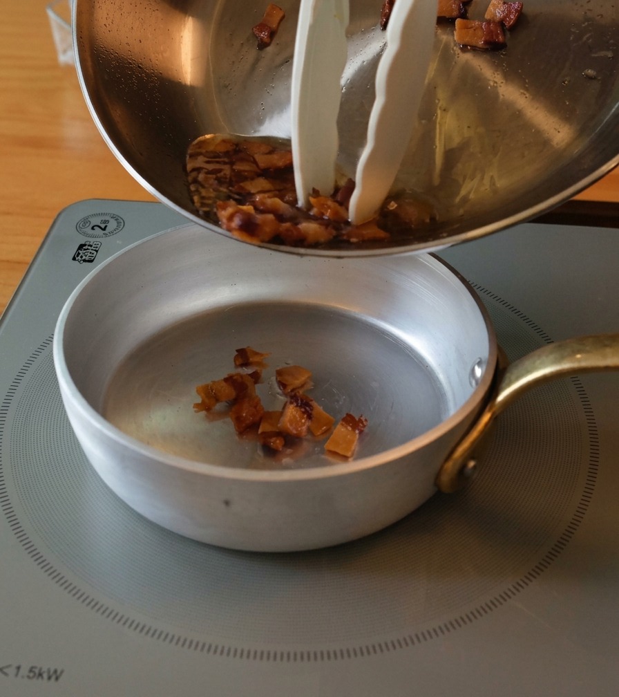 Knuspriger Guanciale und flüssiges Fett werden in eine kleine Schale umgefüllt.