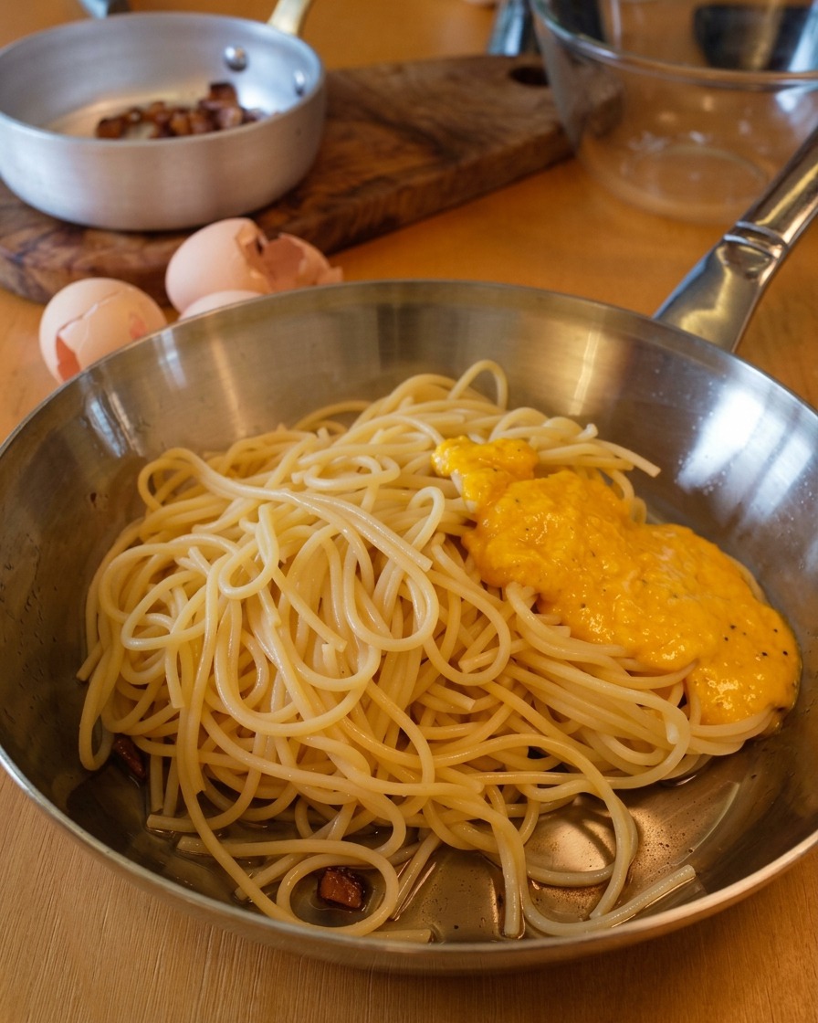 Goldene Ei-Käse-Sauce auf einem Berg Spaghetti in der Pfanne.