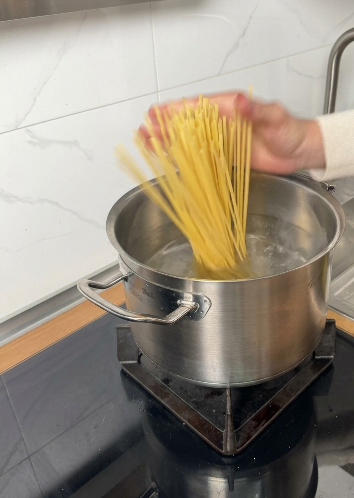 Trockene Linguine werden in einen Topf mit kochendem Wasser gegeben.