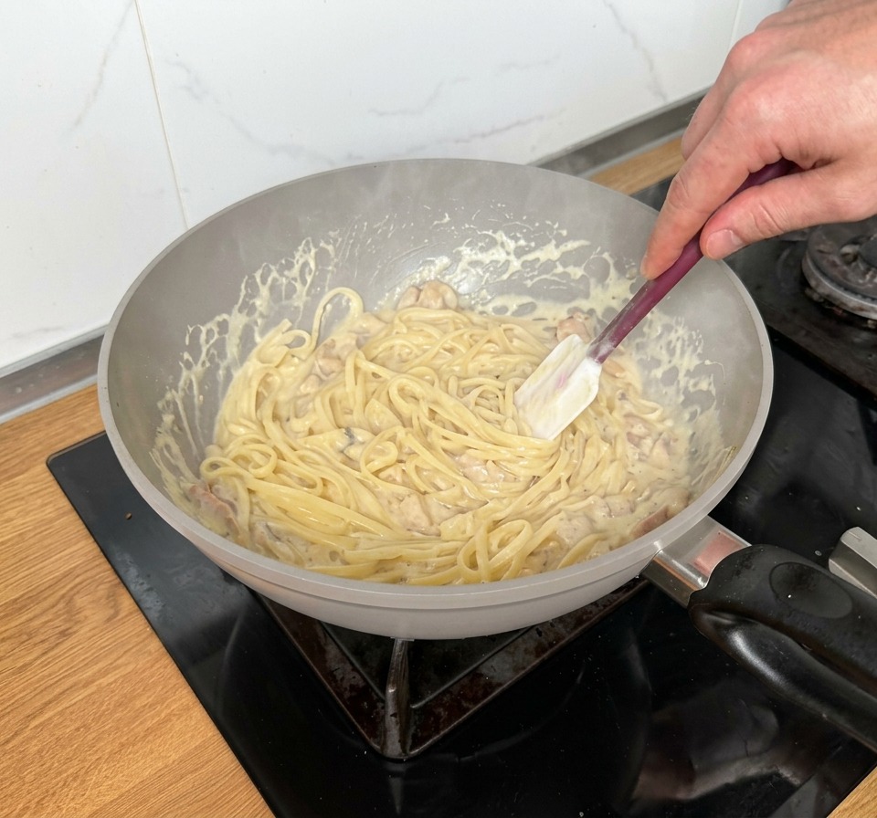 Linguine werden in der cremigen Sauce mit Speck und Pilzen geschwenkt.