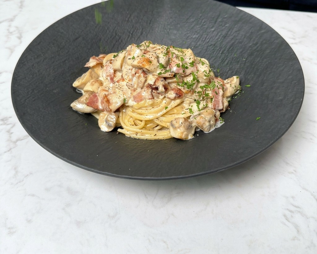 Frische Petersilie wird über den dampfenden Teller mit Pasta gestreut.