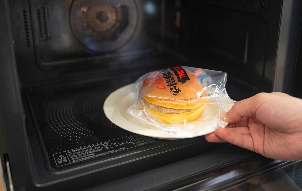 Die obere Hälfte eines getoasteten Brioche-Brötchens wird auf den Burger mit Zwiebeln und Käse gesetzt.