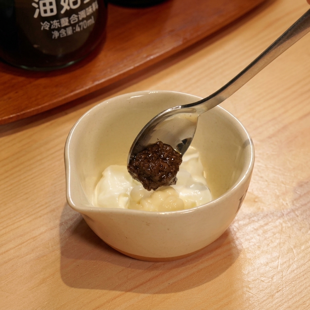 Schwarze Trüffelpaste wird zu der Joghurt-Mayonnaise-Mischung gegeben.