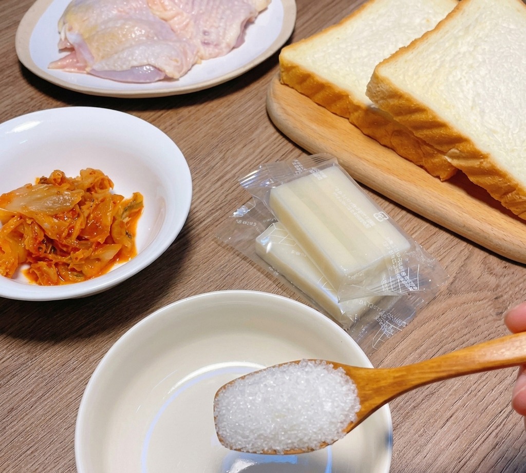Ein Holzlöffel hält Zucker über eine kleine weiße Schüssel mit Zutaten für die Sauce.