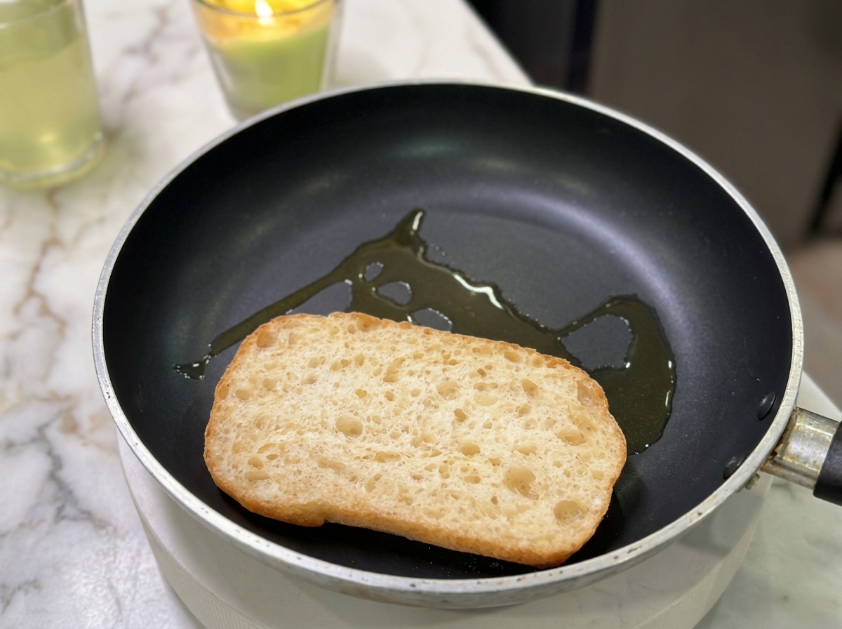 Eine Ciabatta-Hälfte wird mit etwas Öl in einer Pfanne geröstet.