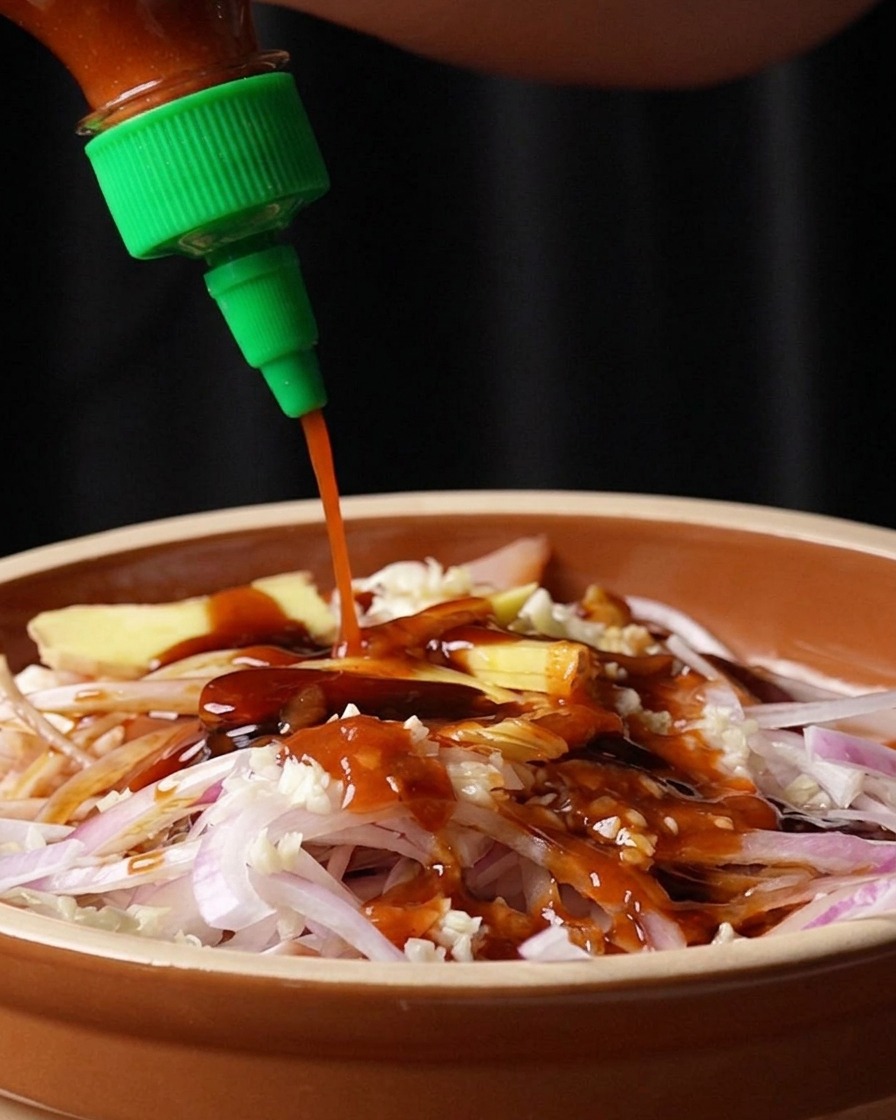 Rote Sriracha-Sauce wird aus einer Flasche auf die Marinade gegeben.