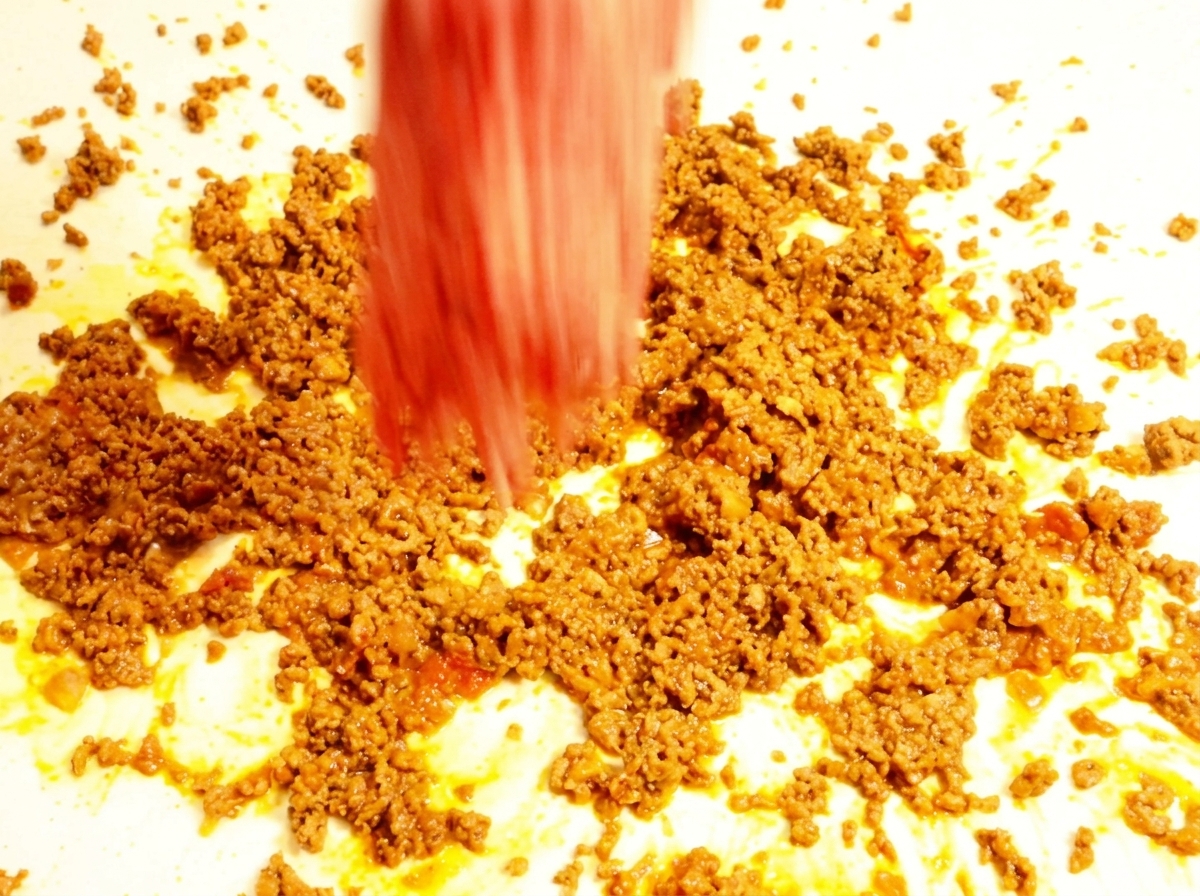 Eingedickte Sloppy-Joe-Füllung blubbert sanft in einer dunklen Pfanne.