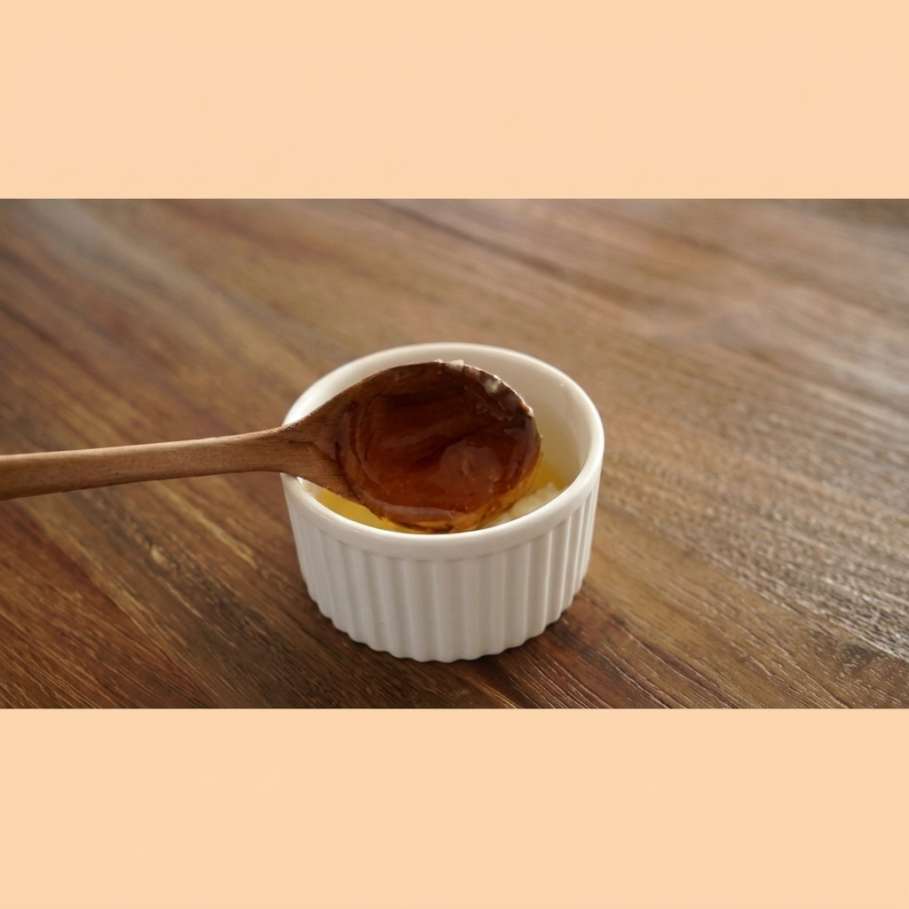 Bernsteinfarbener Honig fließt zähflüssig von einem Holzlöffel in eine weiße Schüssel mit Knoblauchbutter.
