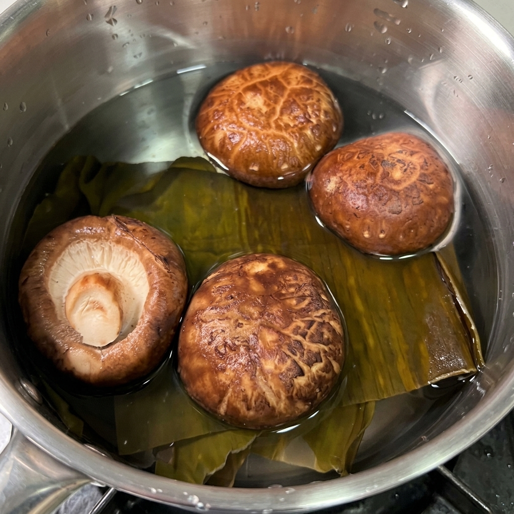 Getrockneter Kombu und braune Shiitake-Pilze weichen in einem kleinen Topf mit klarem Wasser ein.