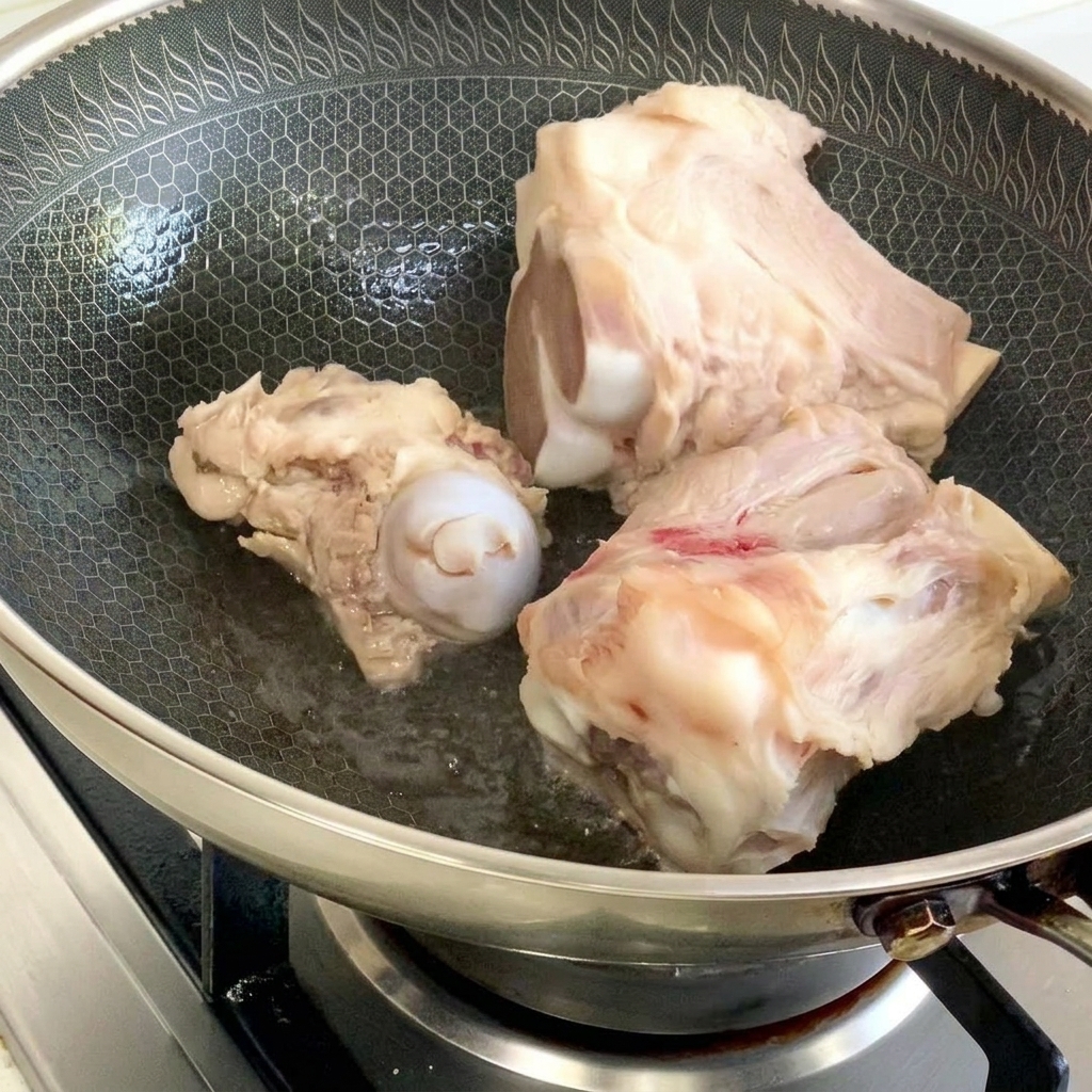 Schweineknochen werden in einem Wok mit etwas Öl goldbraun angebraten.