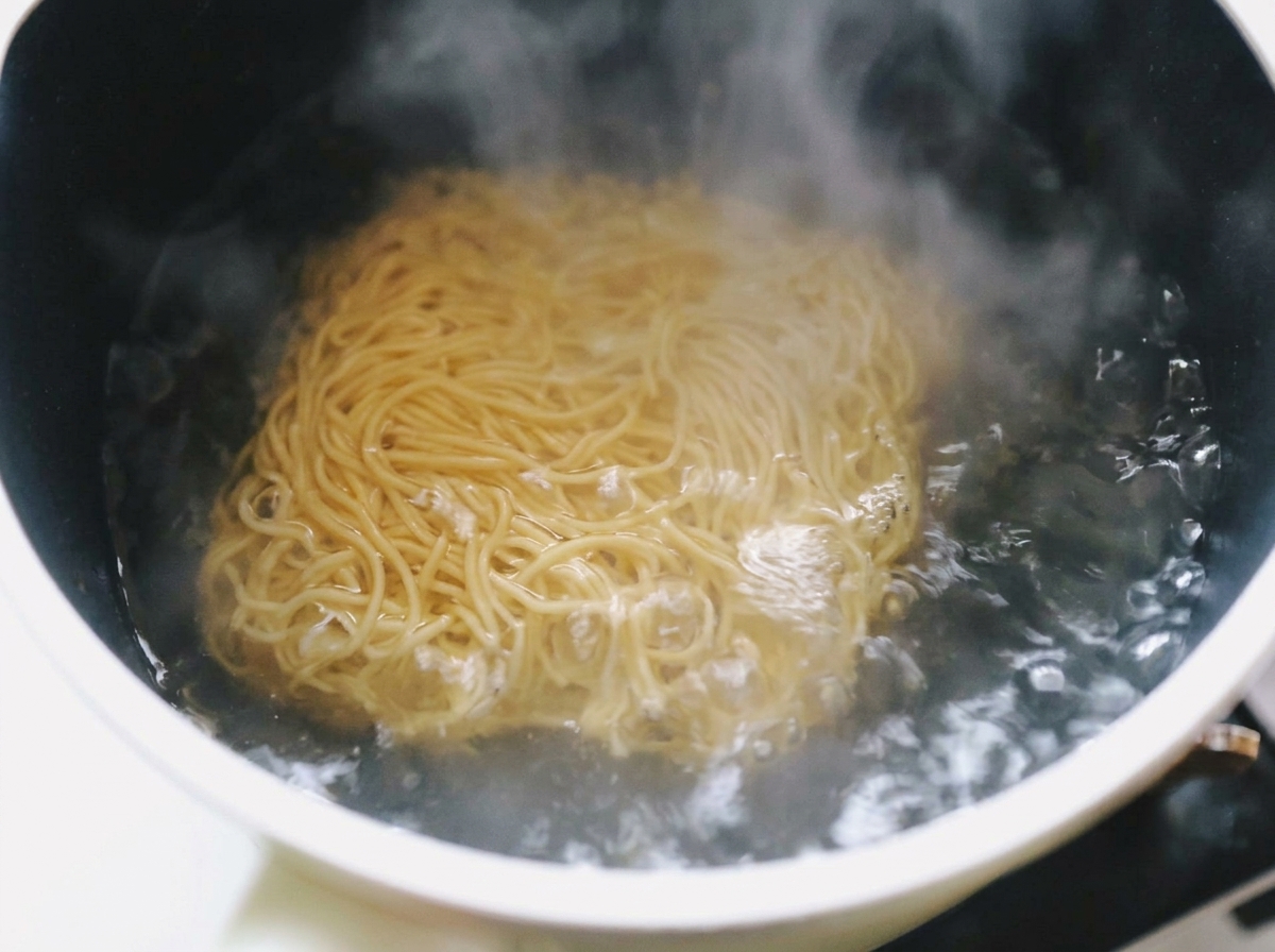Gewellte Ramen-Nudeln kochen in einem Topf mit sprudelndem Wasser.