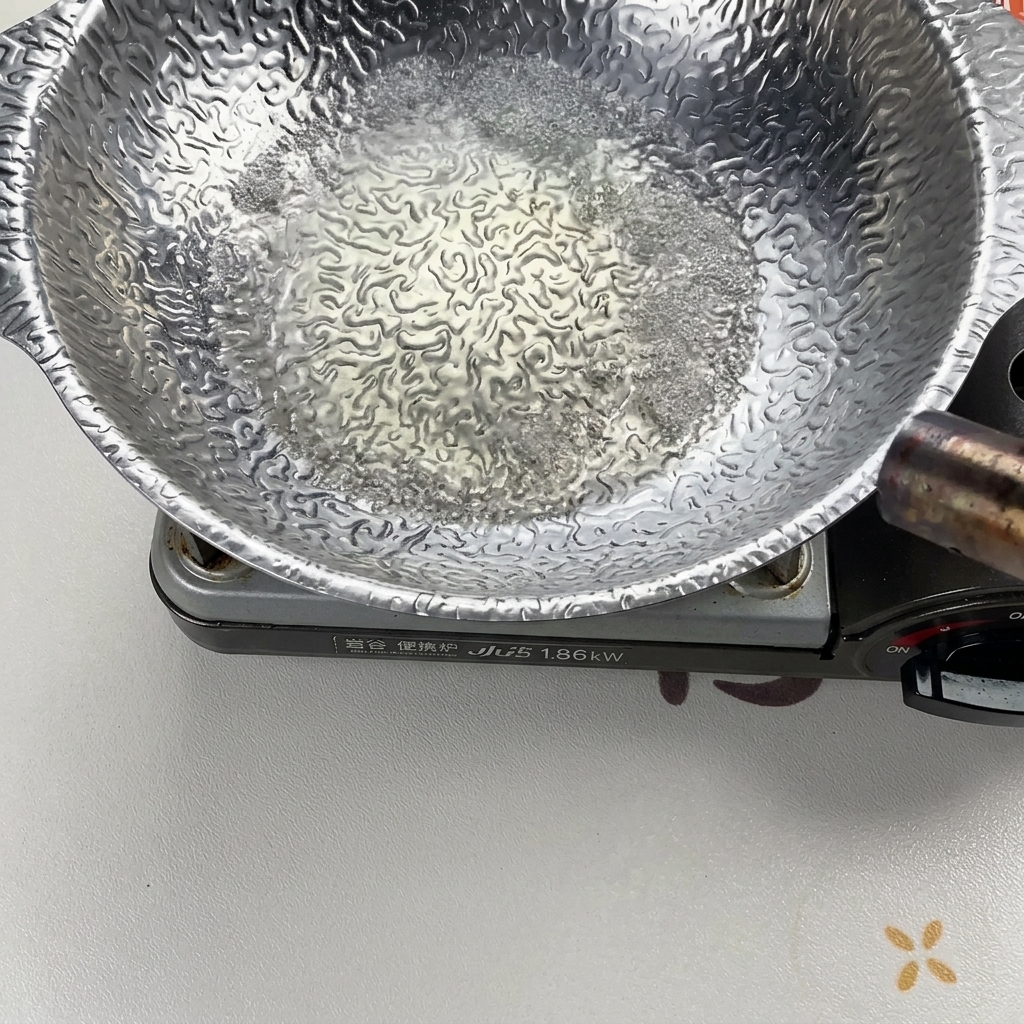 Sprudelnde Flüssigkeit in einem silbernen Kochtopf, die mit einem Flambierbrenner entzündet wird, um den Alkohol zu verbrennen.
