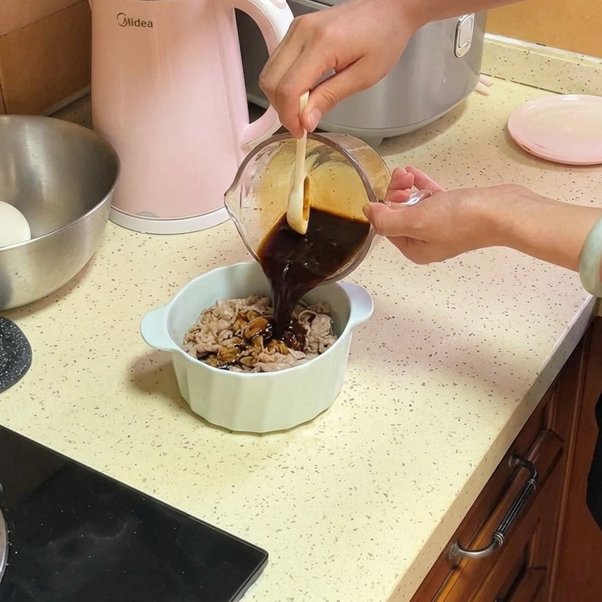 Eine dunkelbraune, würzige Sauce wird aus einem Glasmessbecher über dünne Rindfleischscheiben und Zwiebeln in einer weißen Keramikschüssel gegossen.