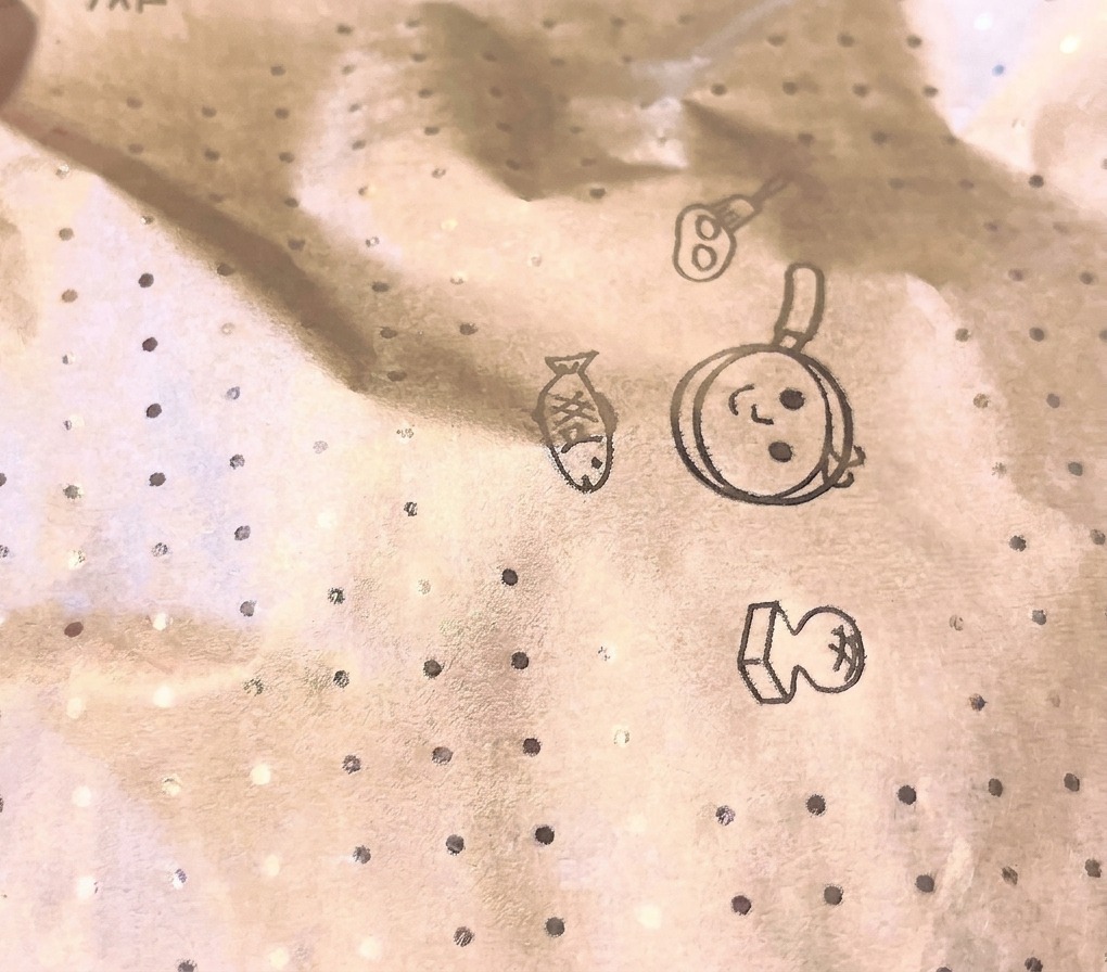 Nahaufnahme eines kreisförmigen Kochpapierdeckels mit illustrierten Küchenmotiven, der eine Pfanne während des Dämpfens abdeckt.