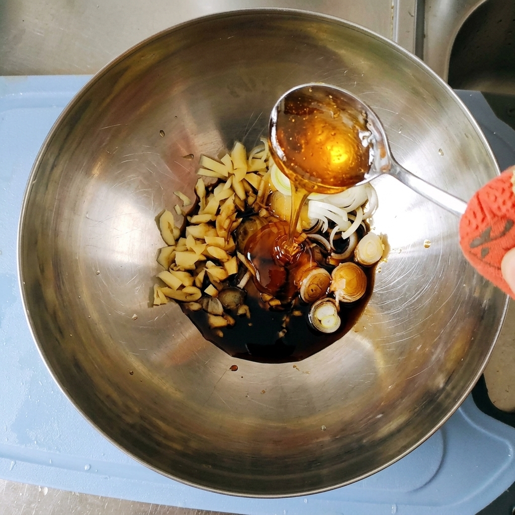 Zähflüssiger, goldener Maissirup wird von einem Silberlöffel in die Marinade in der Metallschüssel gegossen.