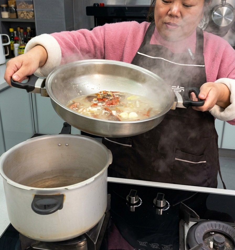 Eine Person gießt eine kräftige Brühe mit gepökelten Rippchen, Knoblauch und getrockneten Chilis aus einer Edelstahlpfanne in einen Schnellkochtopf.