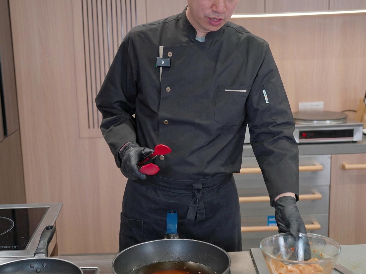 Marinierte Tintenfischstücke garen in einer großen Pfanne mit heißem, brodelndem Öl, während der Koch den Frittiervorgang überwacht.