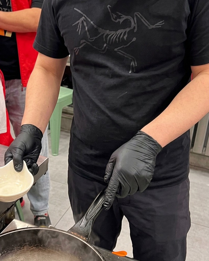 Eingeritzte Tintenfischstücke werden kurz in einem Topf mit kochendem Wasser blanchiert, während Dampf aufsteigt.