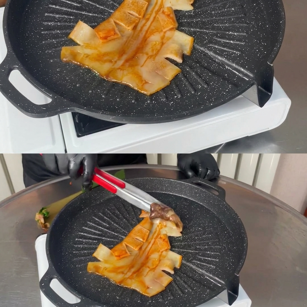 Eine Metallzange legt einen ganzen marinierten Tintenfisch flach in eine heiße, schwarze Grillpfanne.