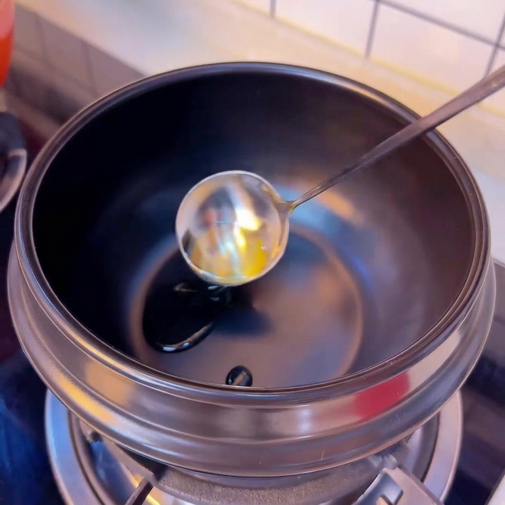 Kamelienöl wird aus einer silbernen Schöpfkelle in einen vorgeheizten schwarzen Tontopf gegossen.