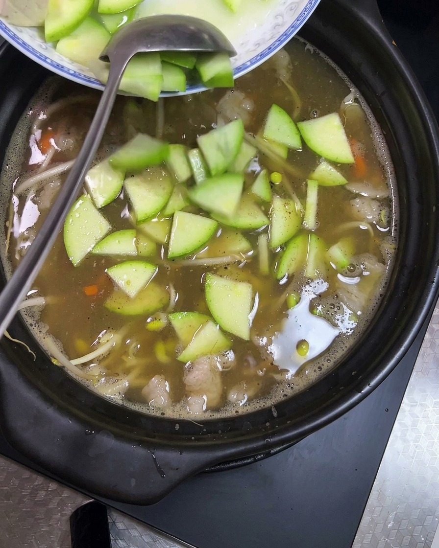 Tofuwürfel und Zucchinischeiben werden in den Eintopf gegeben.