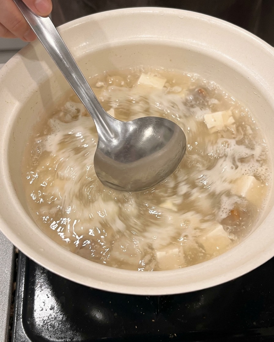 Wasser und Sake werden aus einem Messbecher in einen sauberen Topf gegossen.