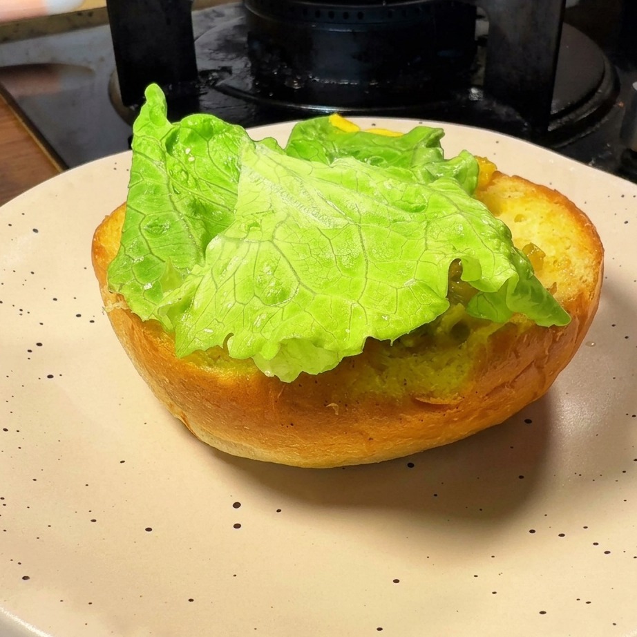 Die angeröstete untere Hälfte eines Burgerbrötchens, belegt mit einem frischen grünen Salatblatt.
