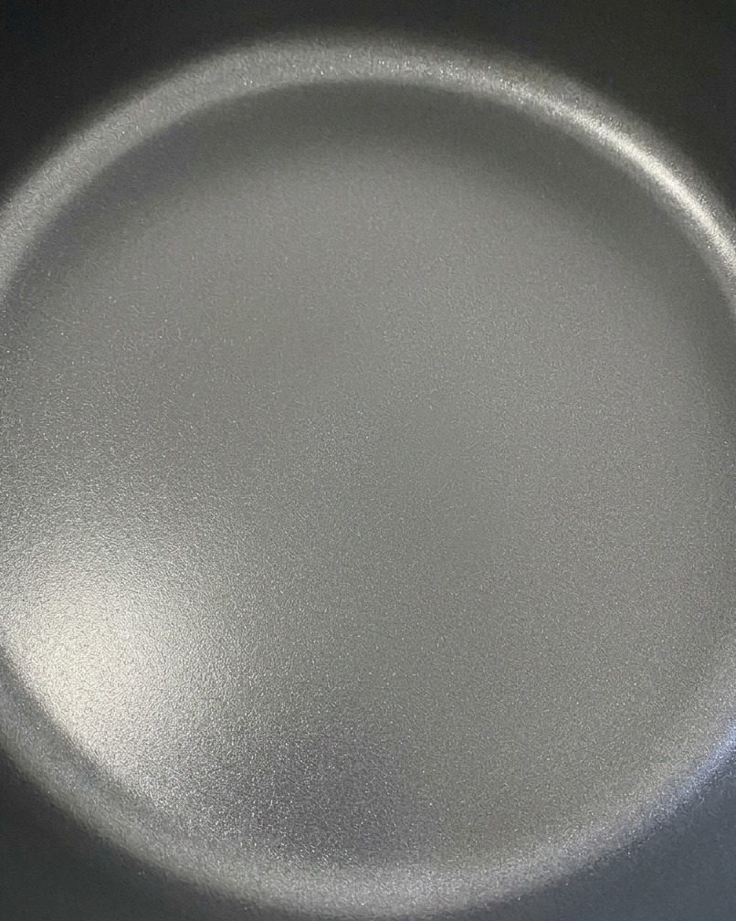 Zwei Scheiben Cheddar-Käse schmelzen wunderbar über den gewürzten Rindfleisch-Patties in einer dunklen Pfanne.