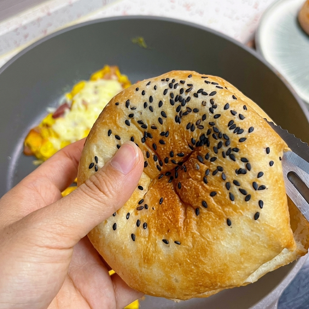 Ein getoastetes Burgerbrötchen mit schwarzem Sesam wird aufgeschnitten.
