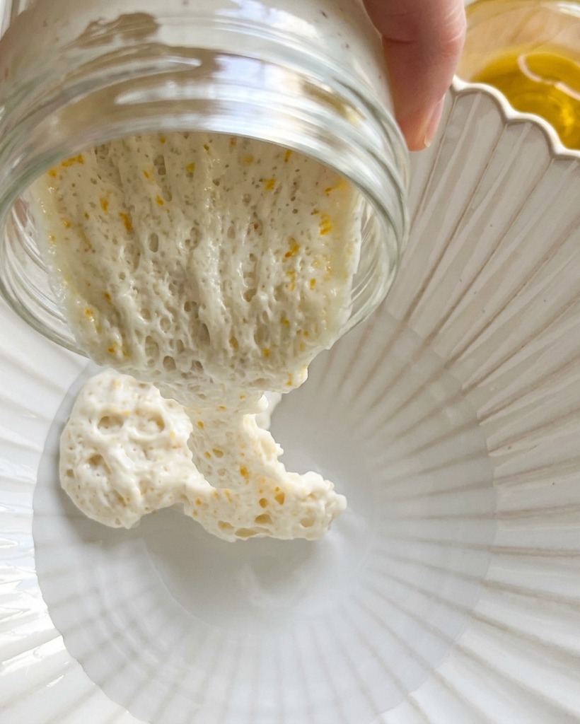 Trockenes Mehl wird in eine Schüssel mit Wasser und dem vorbereiteten Sauerteig gegossen.