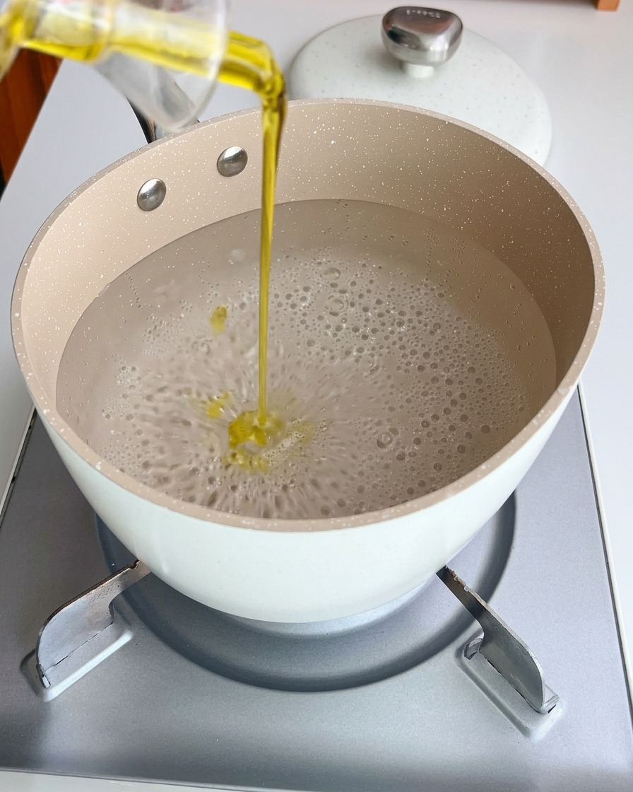 Spaghetti kochen in einem Topf mit Wasser und Öl.