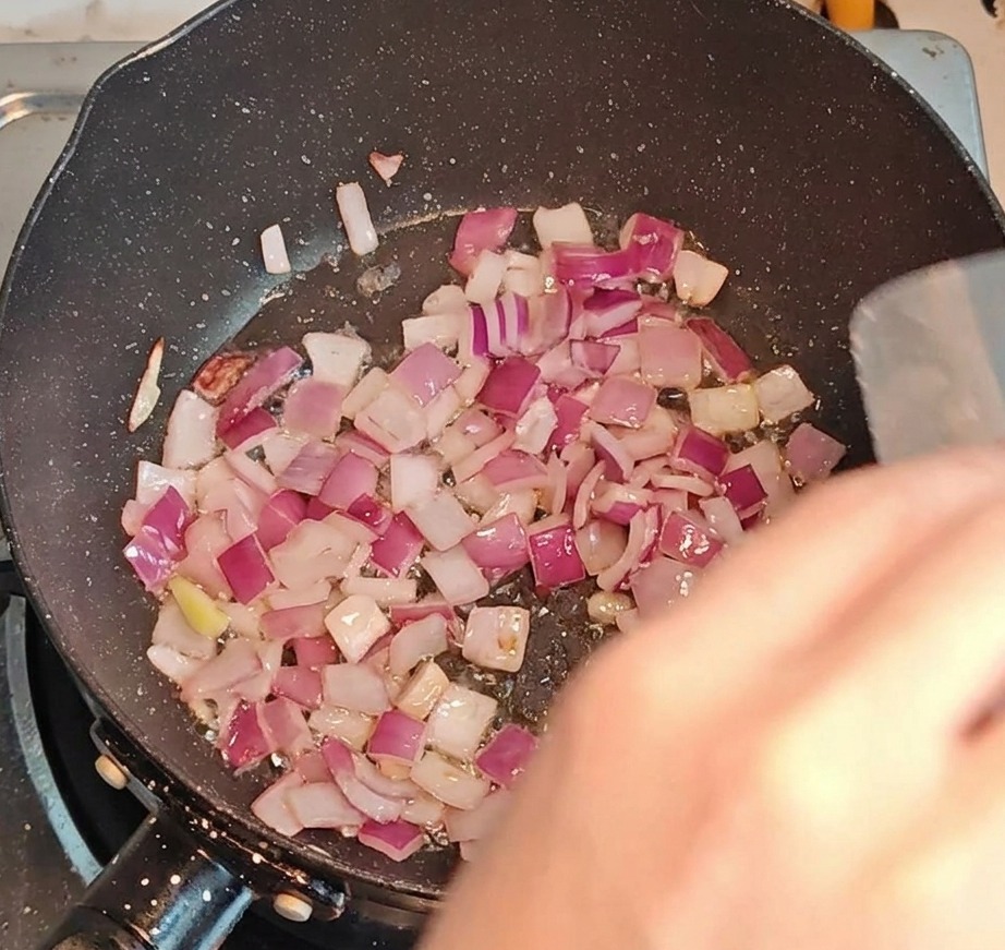 Gewürfelter Speck und Zwiebeln braten zusammen in einer Pfanne bei starker Hitze.