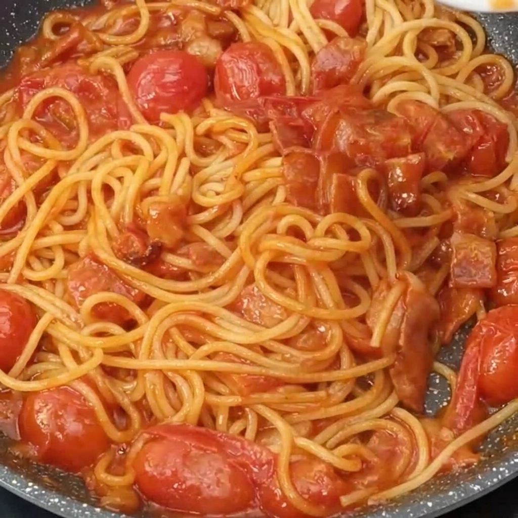 Die fertige Pasta in der Pfanne wird mit geriebenem Käse bestreut.