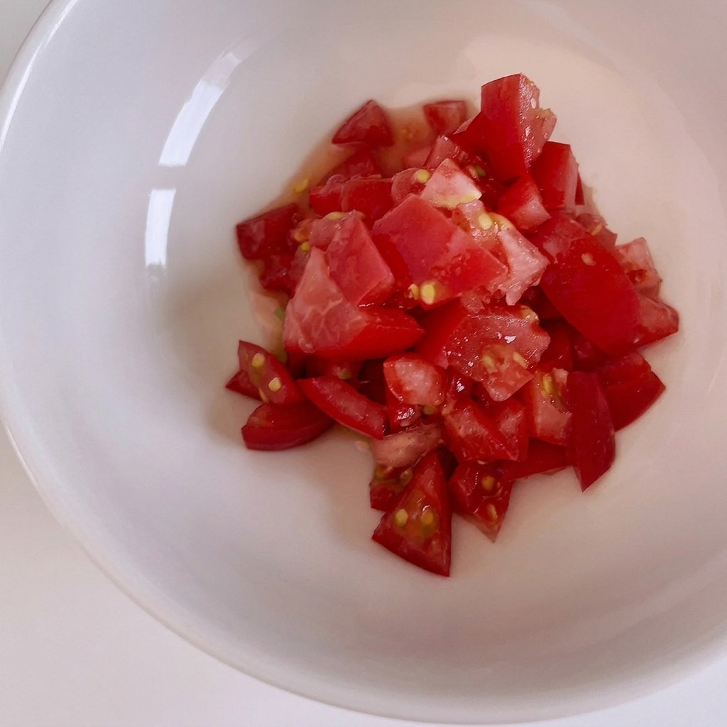 Frische rote Tomaten werden auf einem Holzbrett in kleine Würfel geschnitten.