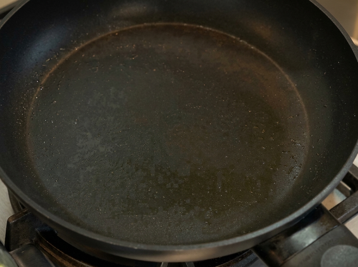 Ein dünner, gestockter gelber Eierpfannkuchen wird in einer beschichteten Pfanne gefaltet.