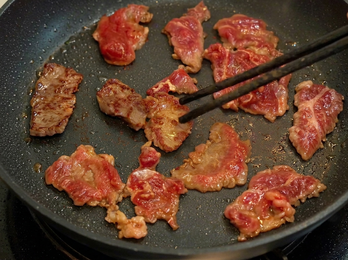 Slices von mariniertem Rindfleisch bräunen in einer heißen Pfanne.