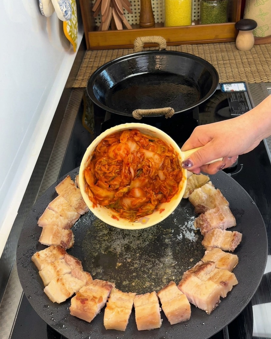 Schweinebauchstücke kreisförmig angeordnet mit Kimchi in der Mitte der Pfanne.