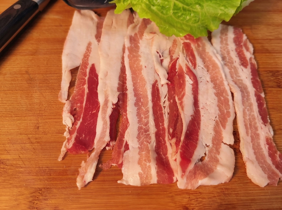 Eine Schweinebauchscheibe belegt mit Salat, Karotte, Zwiebel und Kimchi.