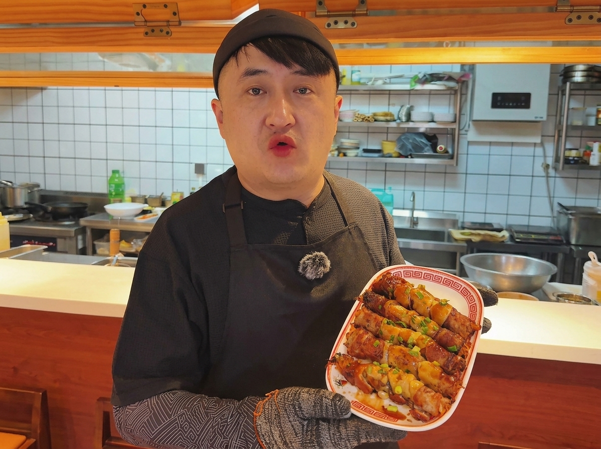 Schweinebauch-Röllchen braten auf einer heißen Eisenplatte, Dampf steigt auf.