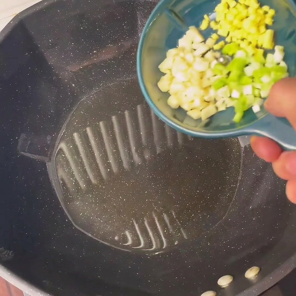 Gehackte Frühlingszwiebeln und Knoblauch brutzeln in heißem Öl in einem Wok.