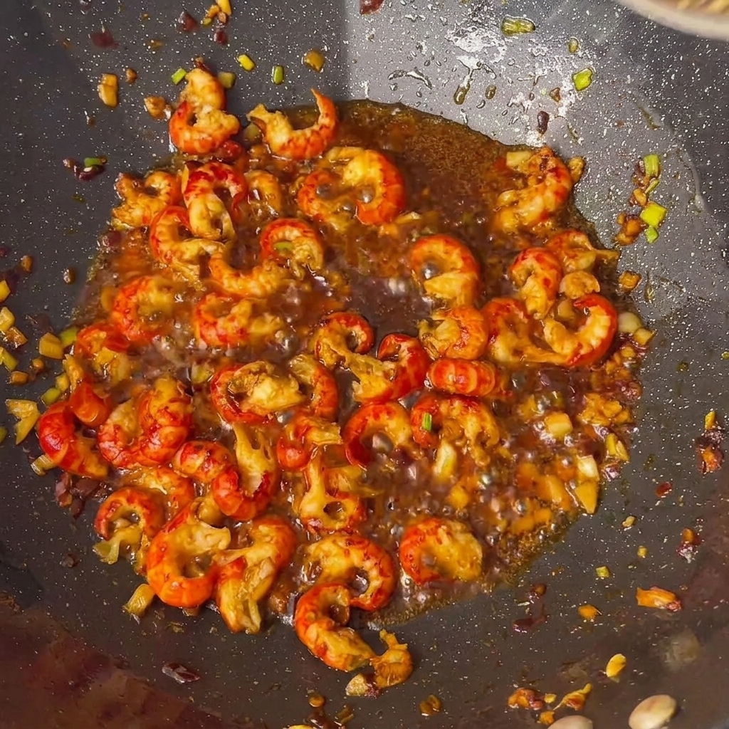 Flusskrebsschwänze werden im Wok mit verschiedenen Saucen und Gewürzen verfeinert.