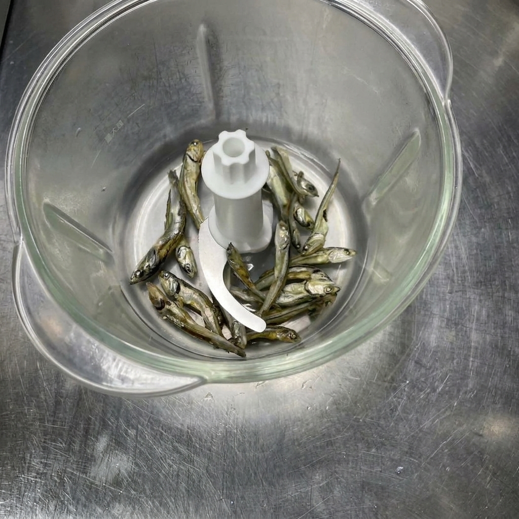 Getrocknete Fischzutaten in einer Küchenmaschine, bevor sie zu Pulver gemahlen werden.