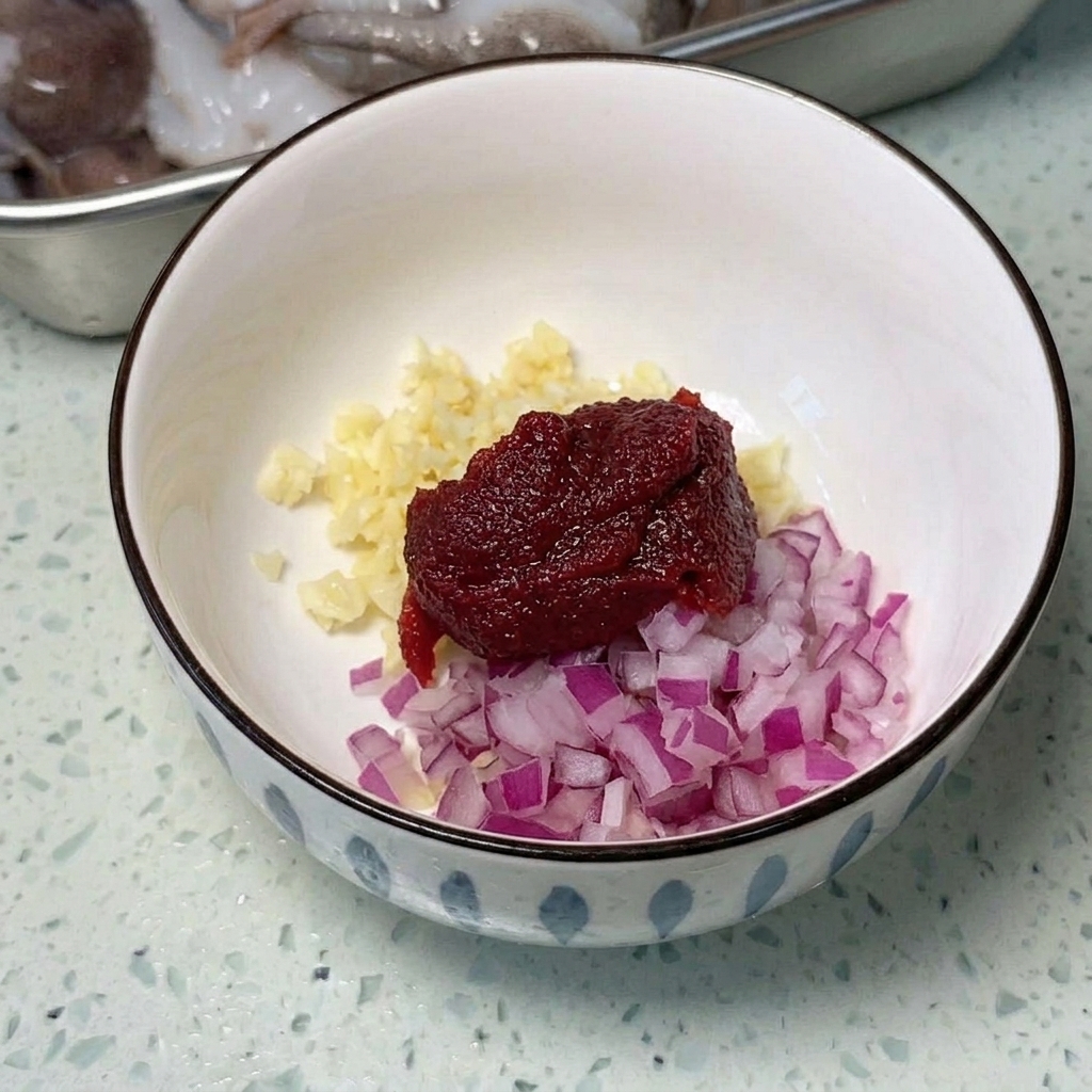 Eine weite Metallpfanne, arrangiert mit geschnittenem Spam, Würstchen und Tofuwürfeln, bereit zum Kochen.