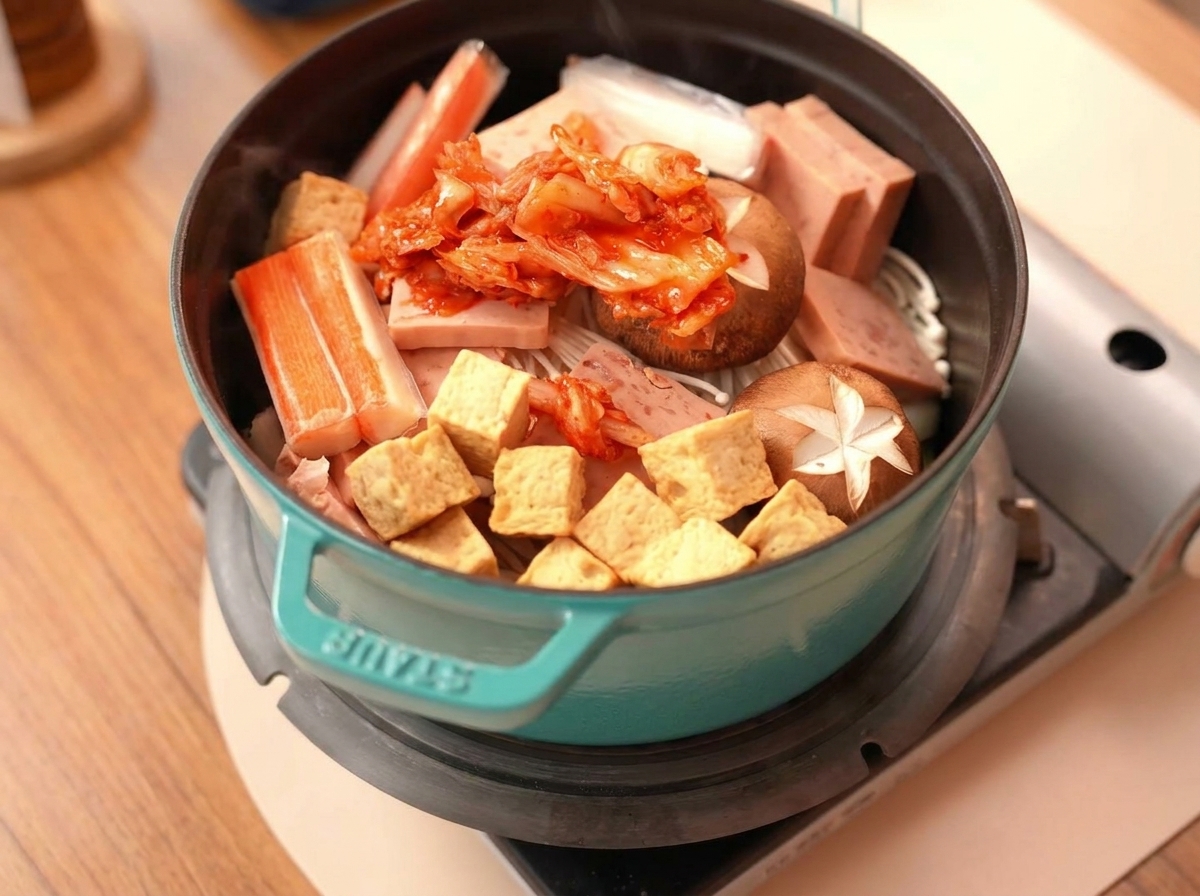 Ein Haufen rotes Kimchi sitzt in der Mitte der vorbereiteten Zutaten.