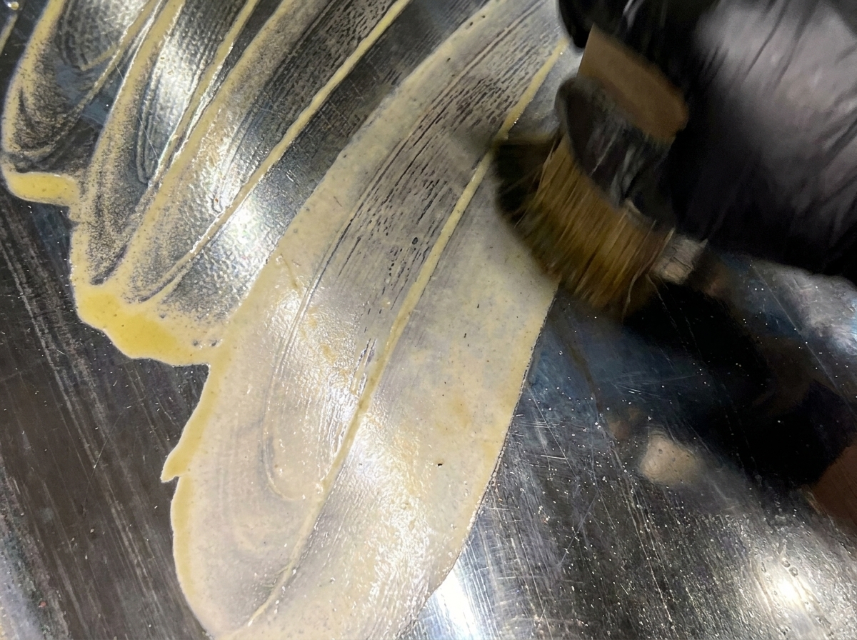 Ein Pinsel verteilt geschmolzene Butter auf einem sauberen, vorgeheizten Flachgrill.