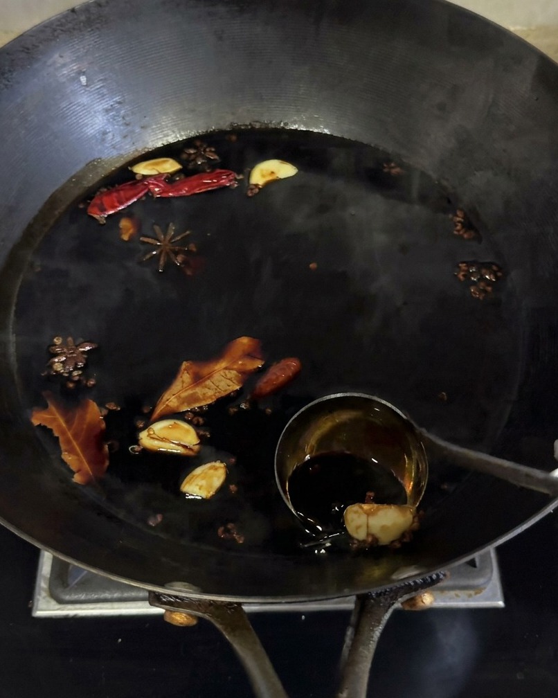 Dunkle Sojasaucen-Marinade köchelt in einem Wok zusammen mit Gewürzen wie Sternanis und Knoblauch.