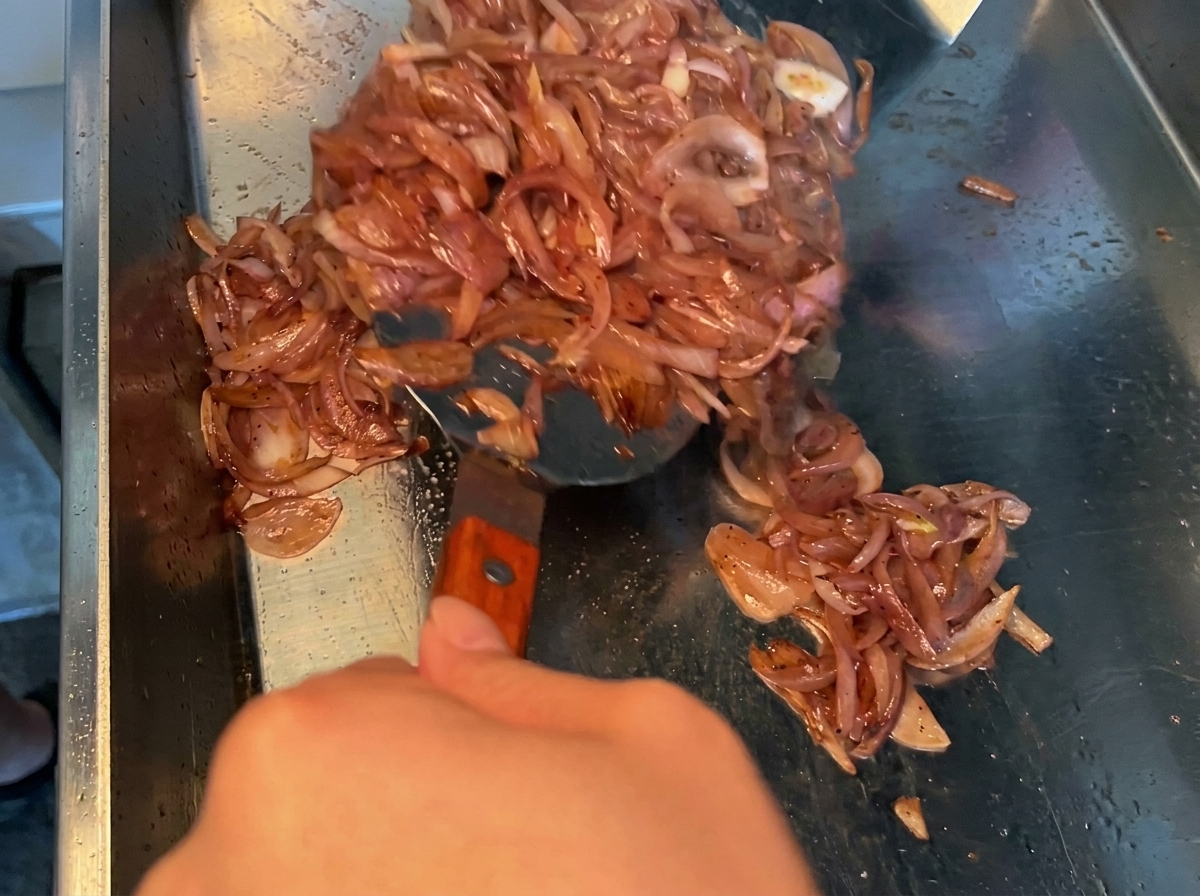 Dunkle Sojasaucenmarinade wird über rohe Schweinebauchstücke in einer Metallschüssel gegossen.