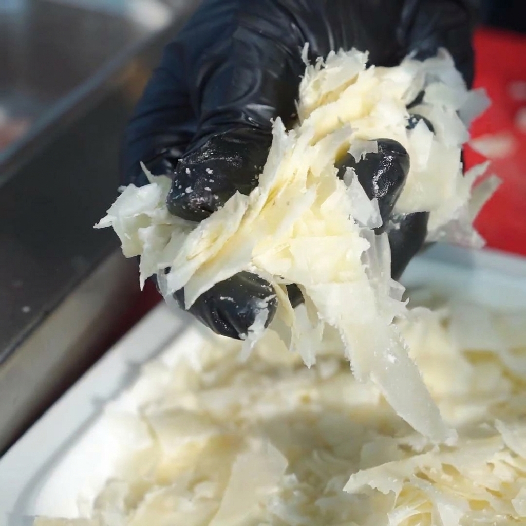 Frische rohe Schweinebauchstreifen, die ordentlich in einer großen Edelstahlschüssel angeordnet sind.